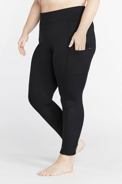 A side view of a model showcasing black leggings equipped with pockets, set against a crisp white background.