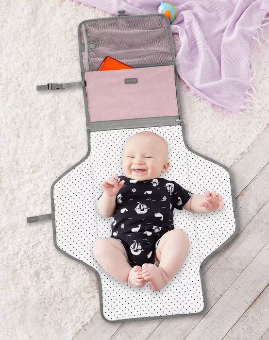 A baby resting on a changing pad included with the diaper changing station