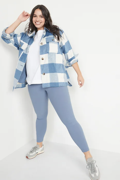 A model wearing light blue ribbed leggings paired with a white t-shirt, blue and white flannel, and sneakers