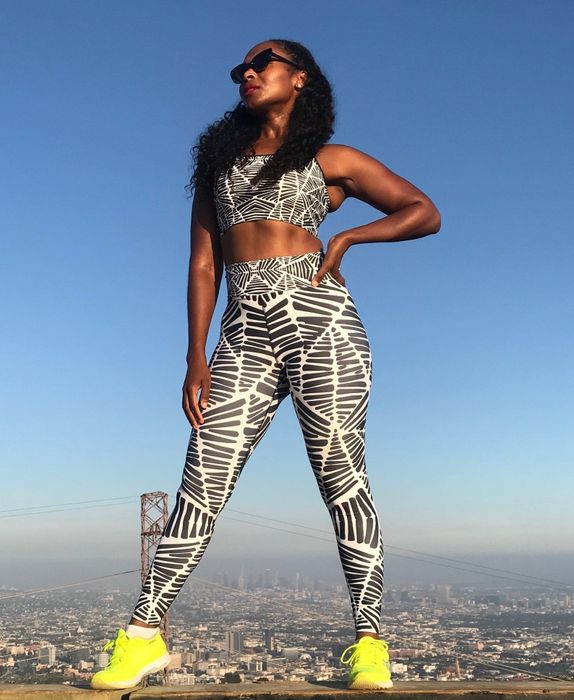 A model wearing black and white zebra-print leggings with a city skyline in the background