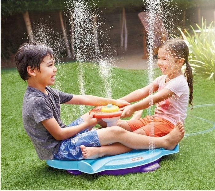 Two children playing on a sprinkler sit-and-spin toy