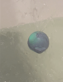a gif showing a whale bath toy spinning and squirting water