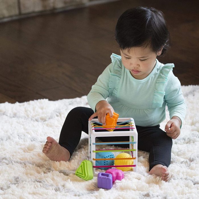 A child playing with the bin filled with elastic bands and colorful shapes