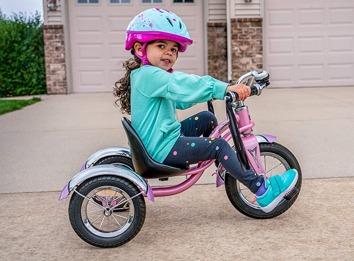 A child model happily riding the pink tricycle.