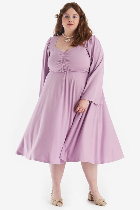 Model wearing a long-sleeve purple midi dress with flare sleeves and cinched detailing on the chest.