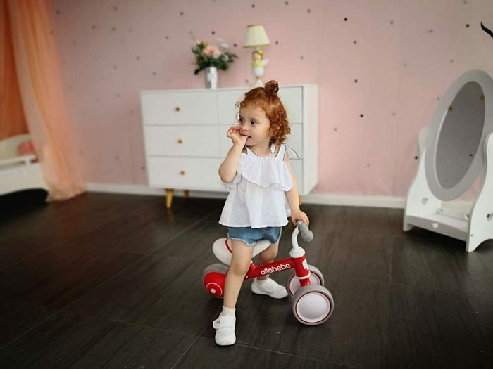 A child riding a red push bike