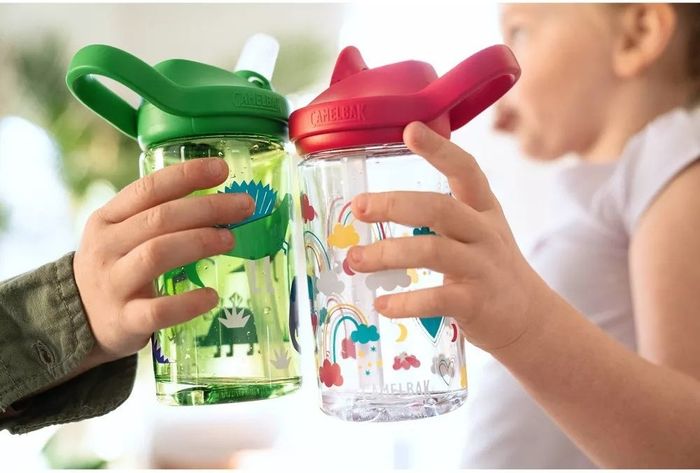 Two children holding clear plastic water bottles adorned with fun artwork