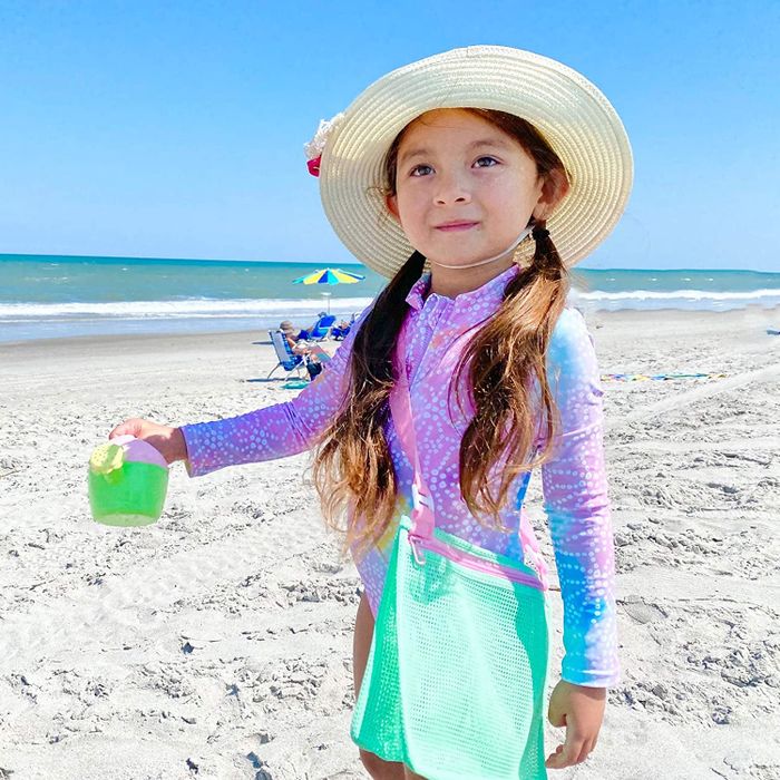 A child with a green mesh bag worn across their torso