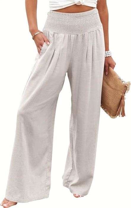 A person in a casual outfit featuring wide-leg trousers and a crop top, carrying a straw bag.