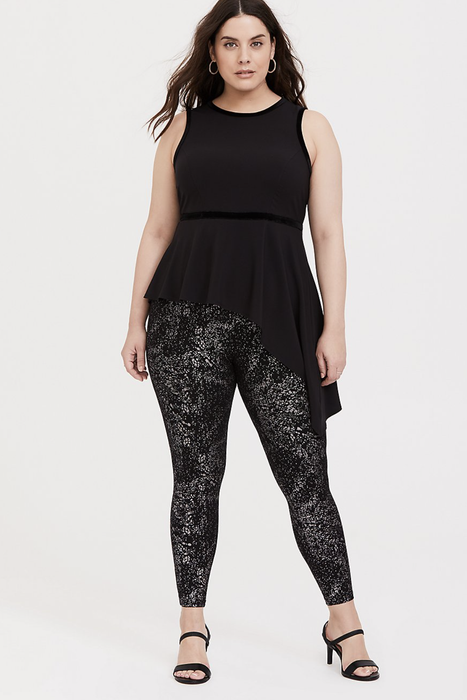 A model is featured in black and silver metallic leggings, complemented by a black tank top and black heels.