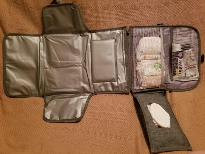 A portable baby changing station featuring a diaper pocket, a holder for baby wipes, and extra storage space for baby cream and other essentials.
