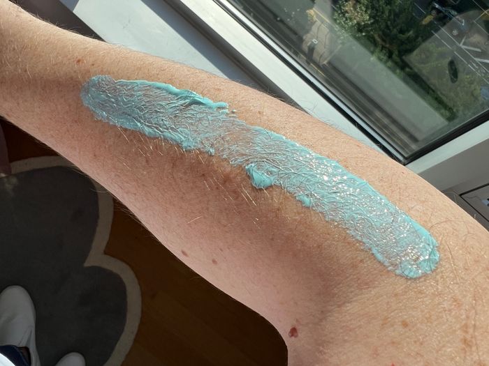 A reviewer's photo of blue Coppertone sunscreen applied to their arm