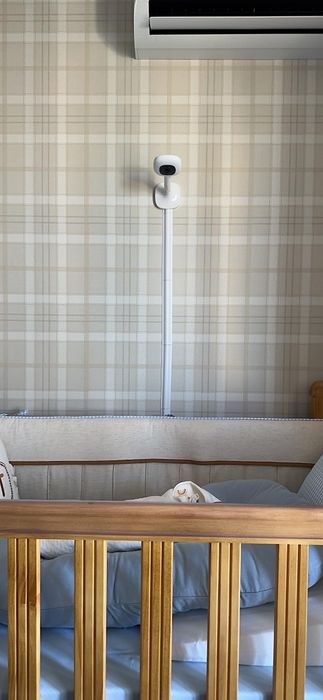 A baby crib with a blanket, pillow, and a baby monitor mounted on the wall above. This image is part of a shopping guide.
