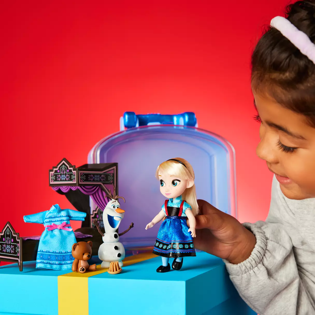 A mini Elsa doll accompanied by an Olaf toy, a bed, a small dress, and a tiny teddy bear