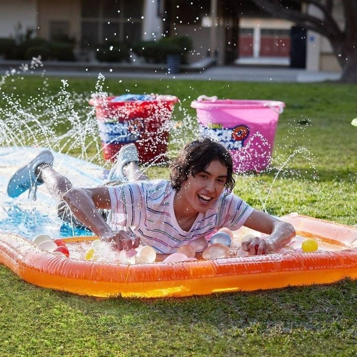 Kid slides on a water slide with water balloons