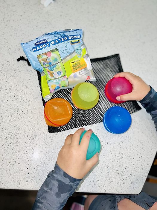 a reviewer holding a set of five multi-colored reusable water balloons