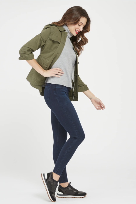 A model sporting blue denim-inspired leggings paired with black sneakers and a green jacket