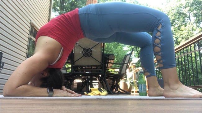 A reviewer is wearing light blue criss-cross cropped leggings while performing a bridge pose.