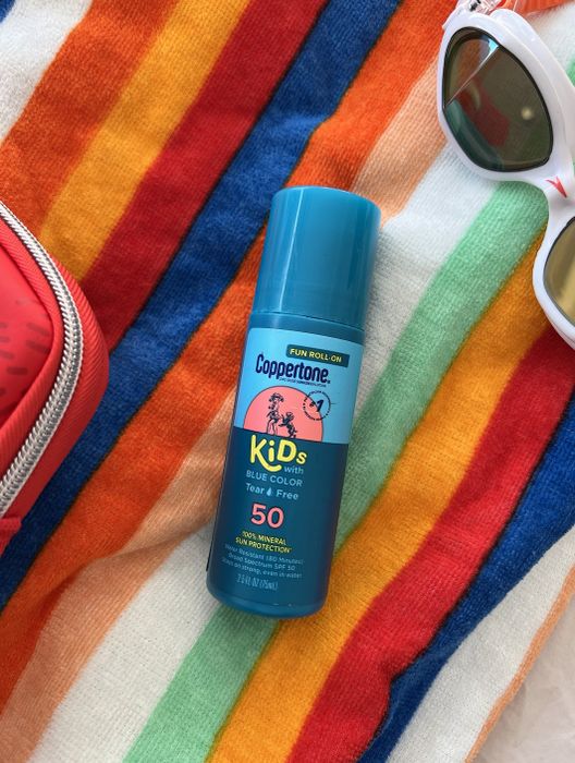 A review photo of the blue Coppertone roll-on sunscreen placed on a beach towel
