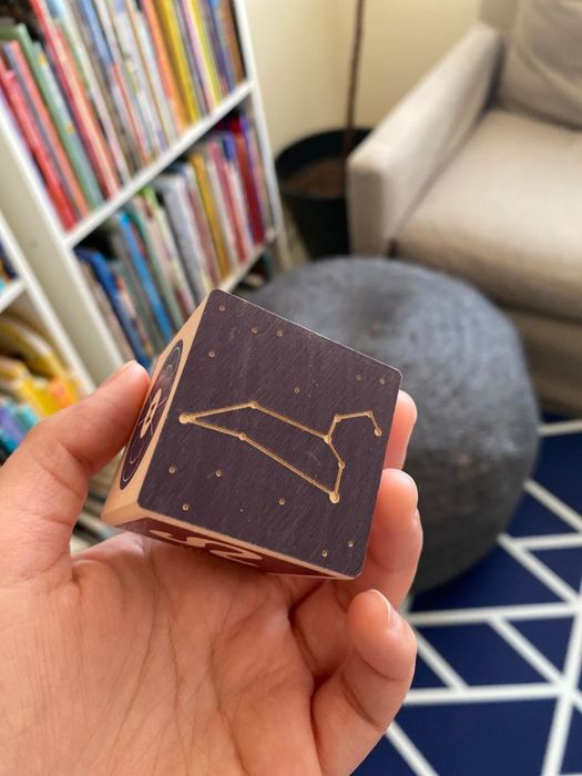 A reviewer's hand holding one of the blocks with a constellation illustration