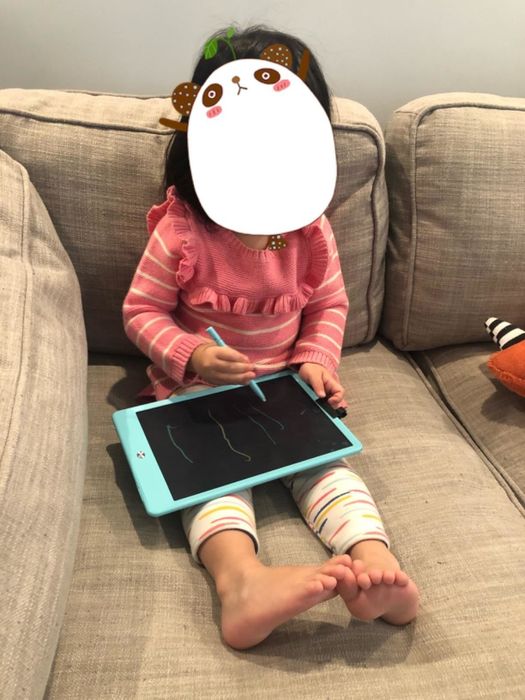 A reviewer's child using the stylus on the blue writing tablet