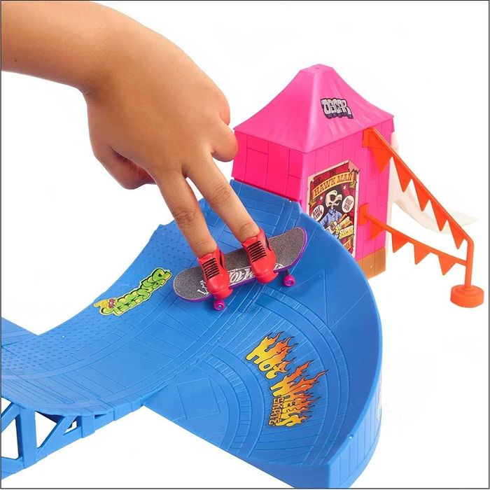 A close-up of the skate ramp toy with a skateboard on two fingers