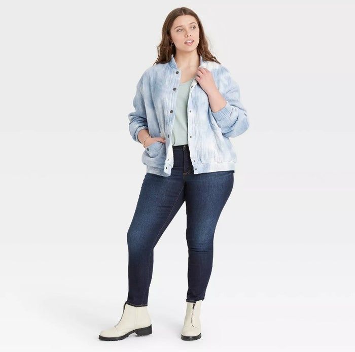 Model sporting a black-and-white jacket over a green shirt paired with jeans