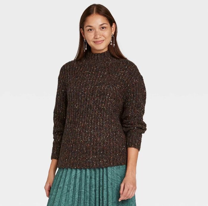 A model styling a brown mock turtleneck sweater paired with a green skirt for a chic, layered look.
