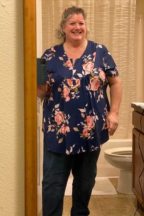 a reviewer wearing the blouse in navy with a pink floral pattern