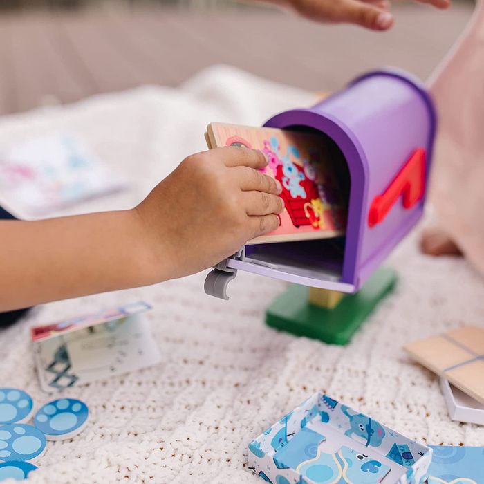 A hand placing pretend mail into the toy mailbox