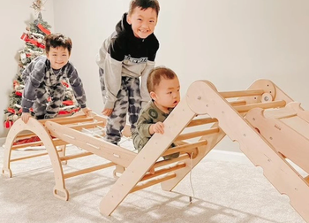 Three children climbing excitedly on the playset, enjoying the adventure