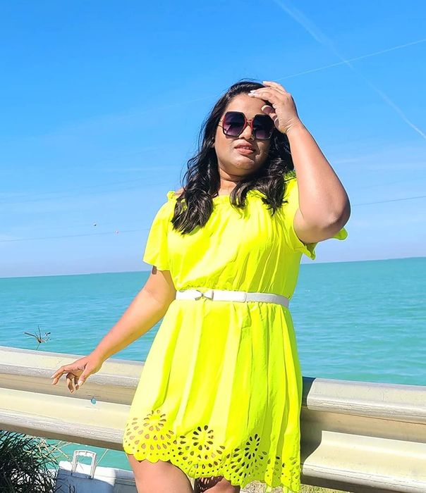another reviewer wearing the yellow version of the dress paired with a white belt