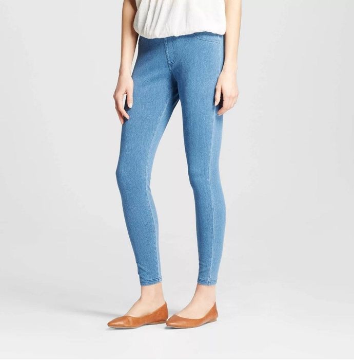 A model is wearing light wash jean-colored jeggings paired with copper ballet flats.