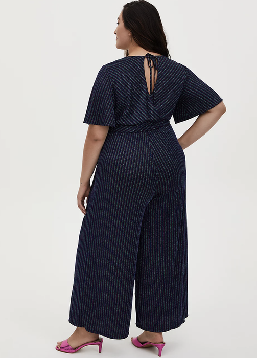 The model is showing the back of a Torrid jumpsuit.