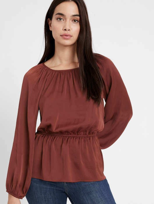 The model is styled in a peplum top in a rich burnt caramel brown.