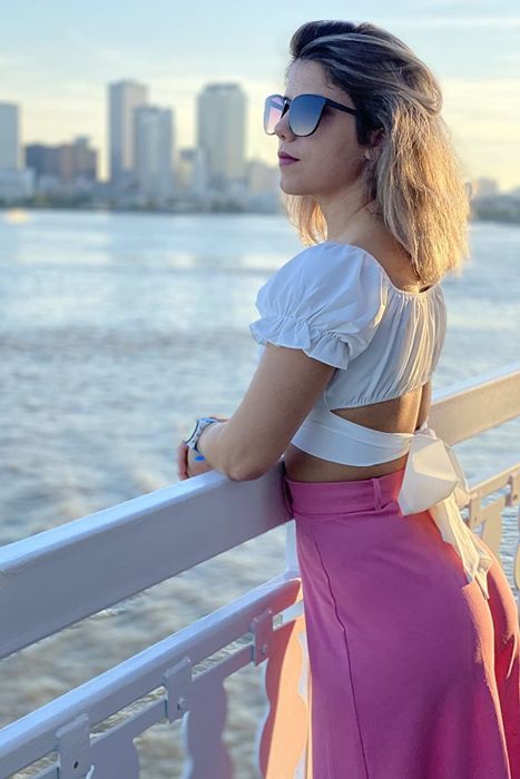 a reviewer showcasing a pink skirt paired with the white crop top, highlighting the tie-back detail