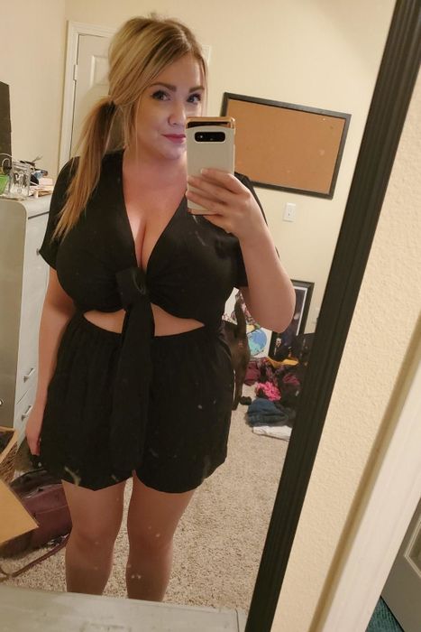 front view of a reviewer wearing the black version of the tie-front romper
