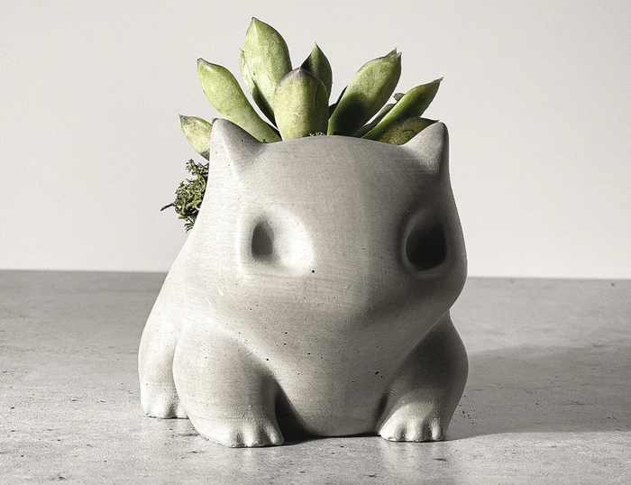 a concrete planter shaped like the Pokémon Bulbasaur, complete with a succulent inside