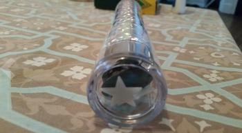 A close-up view of a cylindrical wand with a star shape visible through one end, placed delicately on a patterned tablecloth.