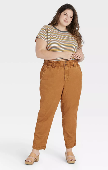Model showcasing high-waisted brown pants paired with a striped shirt for a casual chic look.