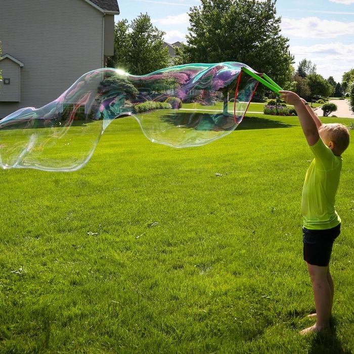 Reviewer photo of their child using the bubble wand to create an enormous bubble