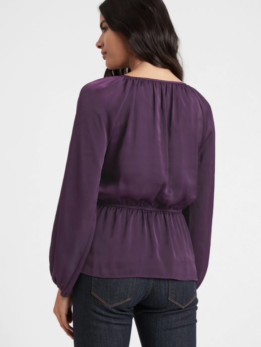 The model is wearing a peplum top in the elegant shade of evening sky blue.