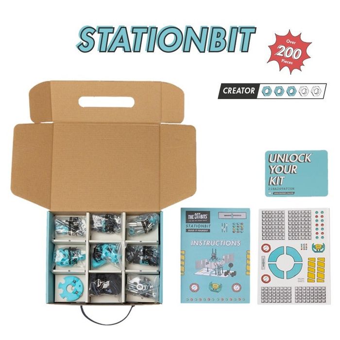 An opened StationBit box displaying all the parts, instructions, and stickers included