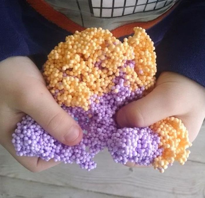 A reviewer squeezing the purple and orange foam balls with their hands, enjoying the squishy texture.