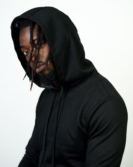 The model is styled in a black satin-lined Kin Apparel hoodie.