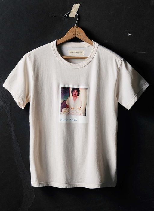 A T-shirt displayed on a hanger, featuring a printed photo of a person with the phrase