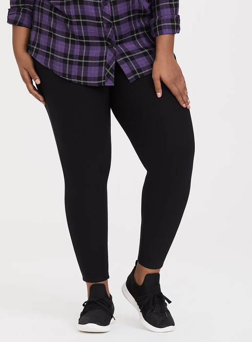 A model is wearing black Torrid fleece-lined leggings.