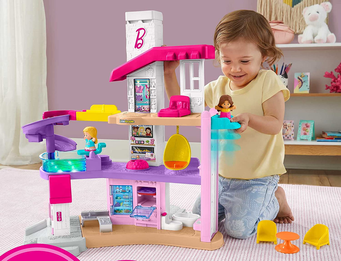 A child playing with the white, pink, and purple-themed playhouse