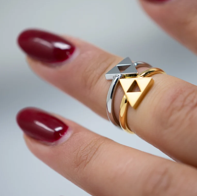 a silver and a gold Triforce ring worn on a finger