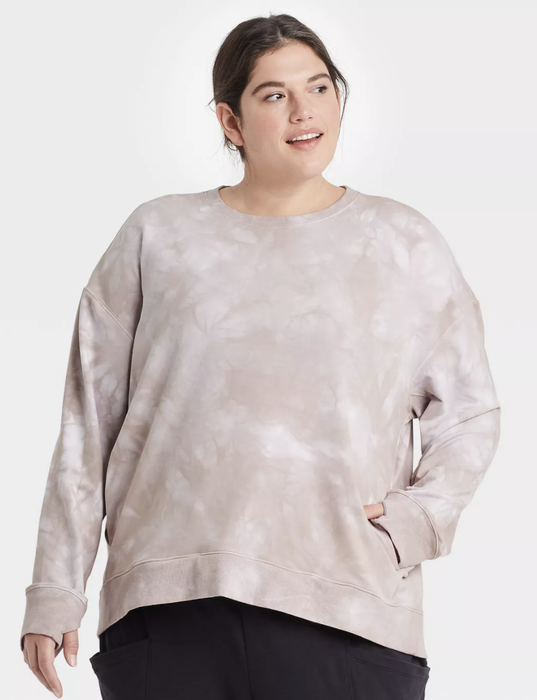 A model showing off a gray tie-dye crewneck with a relaxed fit.